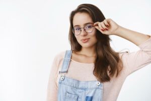 mulher branca segurando a sua armação de óculos feminina